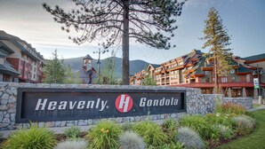 Une enseigne d’hôtel arborant la marque « Heavenly Gondola », entourée de parterres aménagés et avec une chaîne de montagnes en arrière-plan.