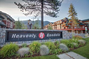 A hotel sign with 'Heavenly Gondola' branding, surrounded by landscaped garden beds and a mountainous backdrop. - Amazing Lakefront Townhome w/Lake & Pool Views, Gas Grill, Steps from Private Beach (South Lake Tahoe)