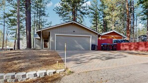 A two-story building with a garage, surrounded by tall trees. - Dog-Friendly Getaway | Deck, Sauna, Grill, Foosball, Parks & Trails (South Lake Tahoe)