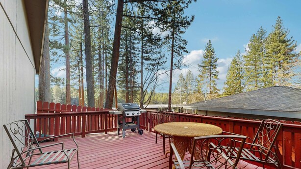 A wooden deck with a grill, chairs, and a table. - Dog-Friendly Getaway | Deck, Sauna, Grill, Foosball, Parks & Trails (South Lake Tahoe)