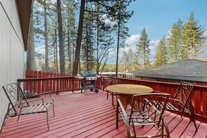 Eine Holzterrasse mit Grill, Stühlen und Tisch.