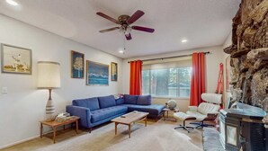 A living room with a sofa, coffee table, fireplace, and a ceiling fan. - Dog-Friendly Getaway | Deck, Sauna, Grill, Foosball, Parks & Trails (South Lake Tahoe)