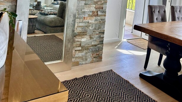 A modern interior with a stone wall, a dining area, and a view through a glass door. - Luxury 5 BR Villa with Pool in St Paul-de-Vence (Saint-Paul-de-Vence)