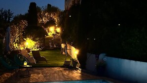 A swimming pool with a paved deck, surrounded by lounge chairs and a well-lit garden area. - Luxury 5 BR Villa with Pool in St Paul-de-Vence (Saint-Paul-de-Vence)