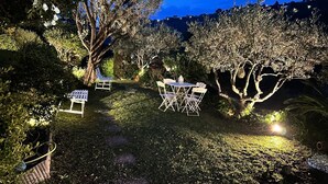 An outdoor garden area with a dining table and chairs, surrounded by trees and shrubs. - Luxury 5 BR Villa with Pool in St Paul-de-Vence (Saint-Paul-de-Vence)