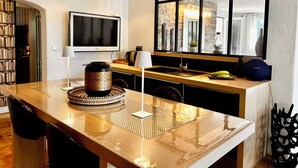 A modern kitchen with a large window, a flat-screen TV, and a dining area with a wooden table. - Luxury 5 BR Villa with Pool in St Paul-de-Vence (Saint-Paul-de-Vence)