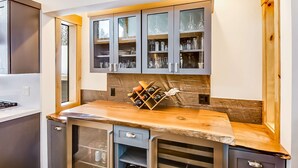 Eine Küche mit Holzarbeitsplatte, eingebauten Schränken und einem Weinkühlschrank.