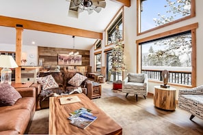 A spacious living room with a fireplace, large windows, and a cozy seating area. - Golf-course home with great view, 2 fireplaces, deck & walkable location (Incline Village)