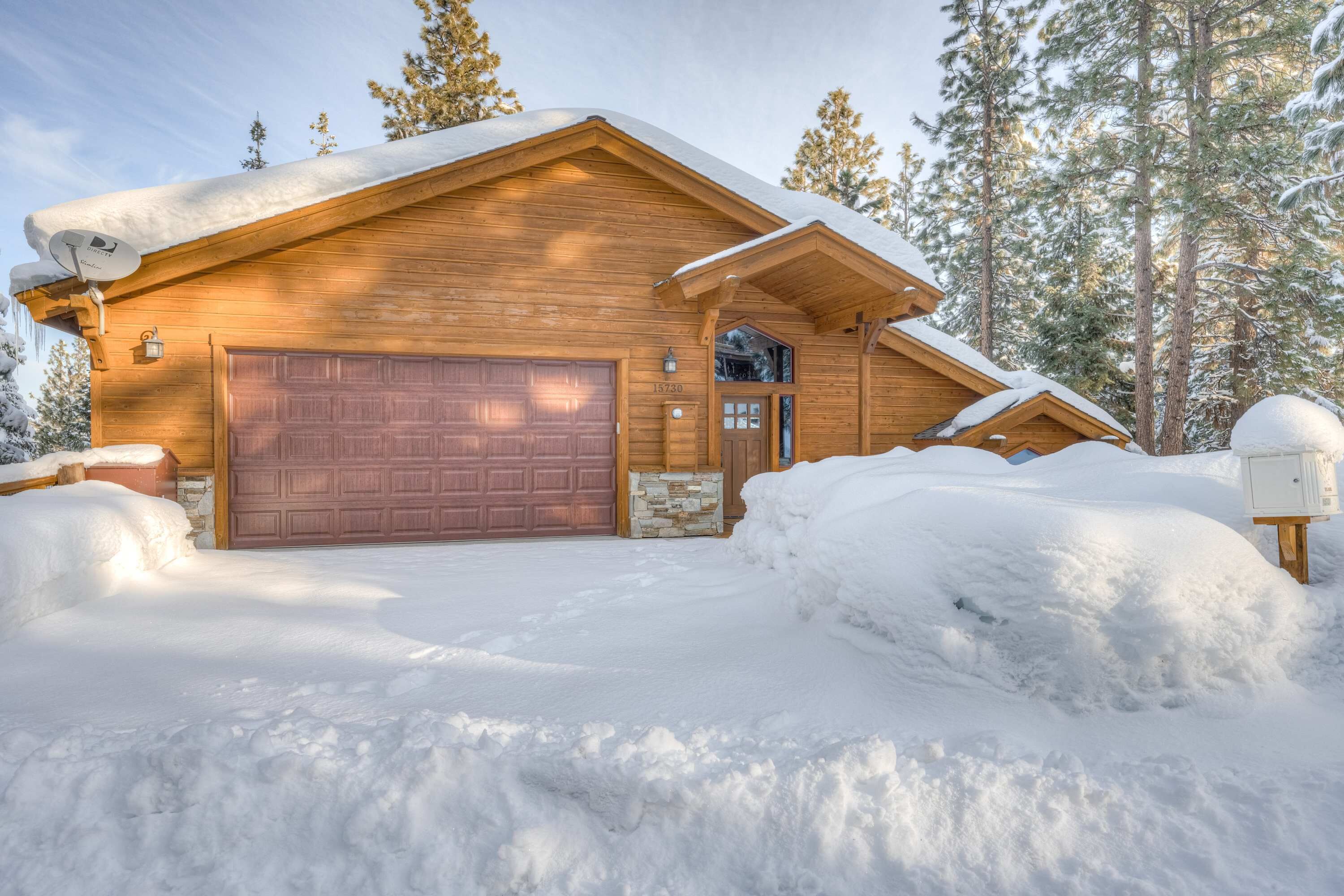 Eine Holzhütte mit Garage, umgeben von Schnee und Bäumen.