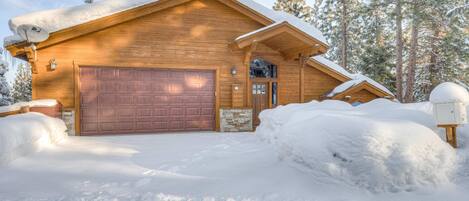Eine Holzhütte mit Garage, umgeben von Schnee und Bäumen.