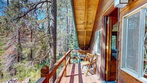 A wooden cabin with a deck, large windows, and a view of the forest. - Riverfront dog-friendly retreat with a rustic flair & wood stove, near skiing (Soda Springs)