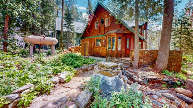 A cabin surrounded by trees, with a stone pathway leading to the entrance. - Riverfront dog-friendly retreat with a rustic flair & wood stove, near skiing (Soda Springs)
