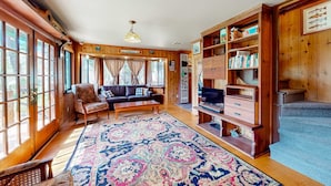 A cozy living room with a large window, a sofa, a coffee table, and a bookshelf. - Riverfront dog-friendly retreat with a rustic flair & wood stove, near skiing (Soda Springs)