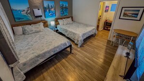 Ein Zimmer mit zwei Betten, Holzboden, einem Schreibtisch und Wandbildern.