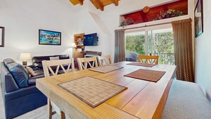 Un comedor con una mesa de madera, sillas y un televisor en la pared.
