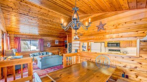 A wooden cabin interior with a dining table, sofa, and kitchen area. - Fun home with foosball table - near on-site golf, pools & hot tub (NorthStar-Truckee)
