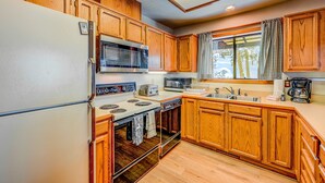A kitchen with wooden cabinets, a refrigerator, a microwave, a stove, and a sink. - Fun home with foosball table - near on-site golf, pools & hot tub (NorthStar-Truckee)