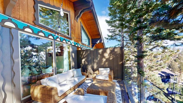Un bâtiment en bois doté de grandes fenêtres, de meubles en osier et offrant une vue sur les arbres.