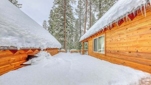 Een houten blokhut met sneeuw bedekte daken en vrij uitzicht op het omliggende bos.