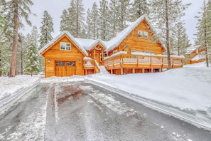 A log cabin with a porch and a driveway.