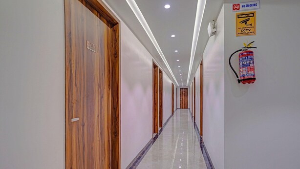 A long, narrow hallway with wooden doors on one side and a fire extinguisher mounted on the wall. - Townhouse Skyboat XLO Point (Nashik)