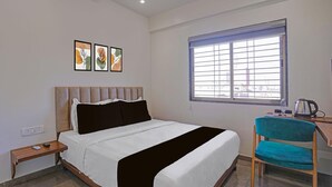 A bedroom with a bed, a desk, a chair, a window, and artwork on the wall. - Townhouse Skyboat XLO Point (Nashik)