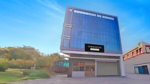 A modern building with a sign reading 'TOWNHOUSE' and a company service label. - Townhouse Skyboat XLO Point (Nashik)