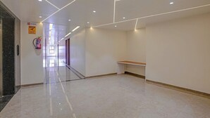 A modern hotel corridor with a marble floor, recessed lighting, a fire extinguisher, and a no-smoking sign. - Townhouse Skyboat XLO Point (Nashik)