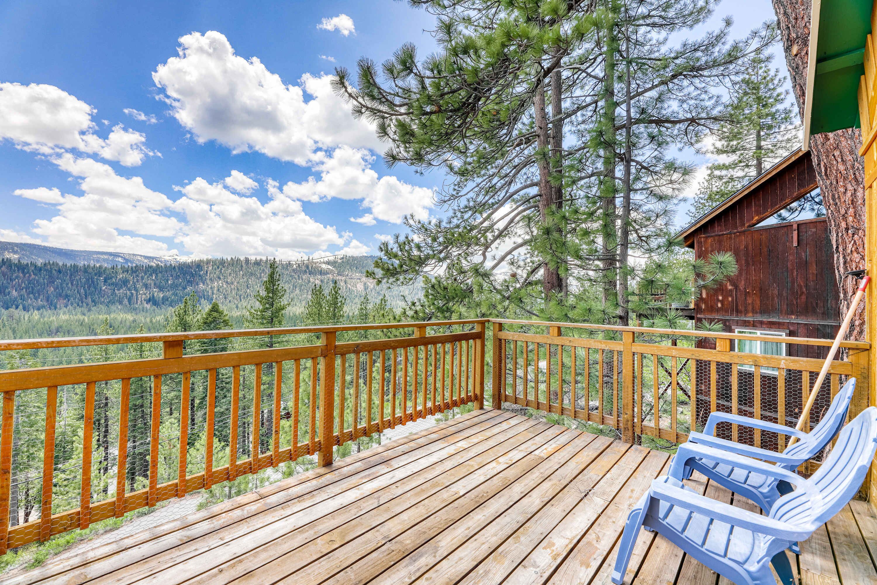A wooden deck with a view of a forest and mountains.