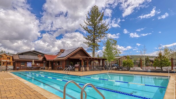 A swimming pool with clear blue water, surrounded by a wooden deck and lounge chairs. - Quiet mountain home w/private deck/gas grill/shared pool - near lakes (Truckee)
