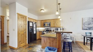 Una cocina moderna con armarios de madera, un refrigerador negro, un microondas y una isla con encimera de granito.