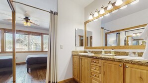Un baño con armarios de madera, un espejo grande y un ventilador de techo.