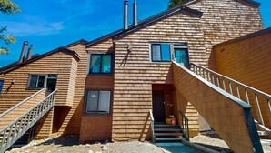 Una cabaña de madera con una escalera, una chimenea y una ventana.