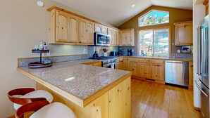 Una cocina con armarios de madera, encimeras de granito, una isla central y vistas al exterior.