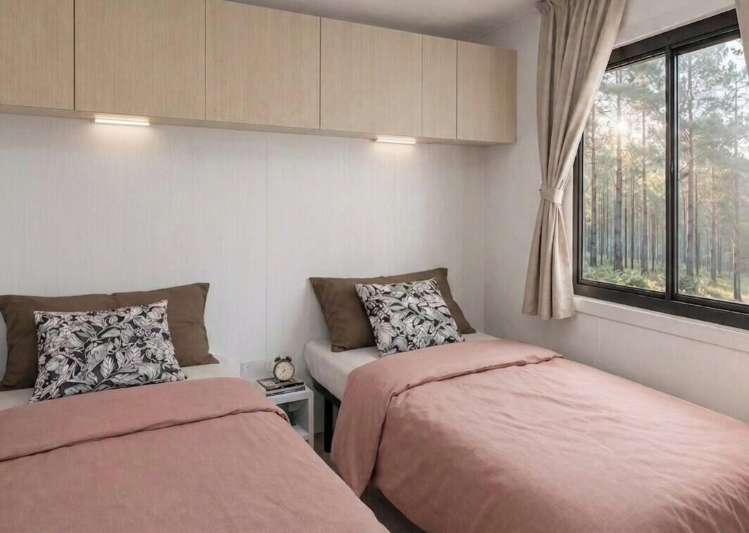 A bedroom with two beds, a nightstand, a window with curtains, and a wooden ceiling.