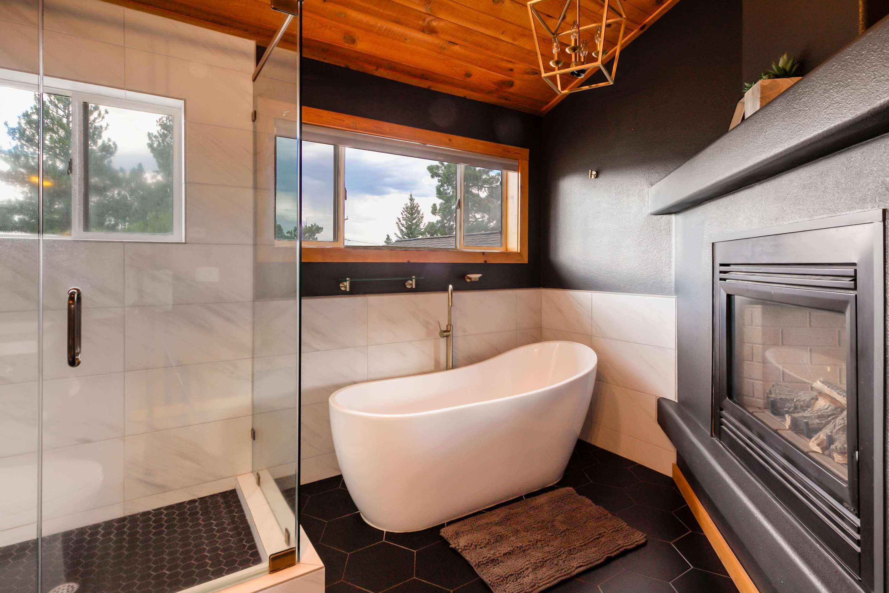 Une salle de bain moderne avec une baignoire sur pieds, une douche à parois de verre et une cheminée.