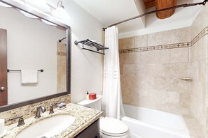 Une salle de bain équipée d’un lavabo, de toilettes, d’une baignoire et d’un rideau de douche.