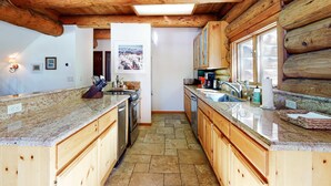A kitchen with wooden cabinets, granite countertops, and a tiled floor. - Dog-Friendly Classic Log Cabin with Game Room, Deck & Views (Truckee)