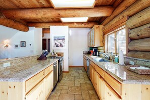 A kitchen with wooden cabinets, granite countertops, and a tiled floor. - Dog-Friendly Classic Log Cabin with Game Room, Deck & Views (Truckee)