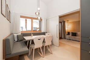 Een moderne woonruimte met een eethoek, een bank, een tafel en uitzicht door een open deur.