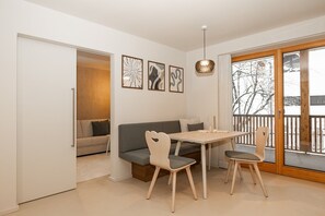 A modern interior with a dining table, chairs, a sofa, and a balcony with a view. - Apartment “N°1” with Mountain View, Private Terrace and Wi-Fi (Hüttschlag)