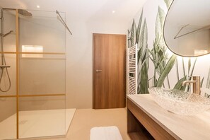 A modern bathroom with a glass shower enclosure, a wooden door, a sink with a decorative bowl, and a large mirror. - Apartment “N°1” with Mountain View, Private Terrace and Wi-Fi (Hüttschlag)