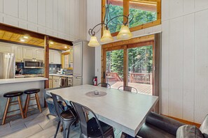 A spacious kitchen with modern appliances, a dining area with a large table and bar stools, and a view of a wooden deck. - Wonderful Lodging with Private Hot Tub, Shared Pool & Amenities, & Large Deck (Truckee)