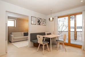 A modern living room with a sofa, a dining table with chairs, and a balcony with a view. - Apartment “N°2” with Mountain View, Private Terrace and Wi-Fi (Hüttschlag)