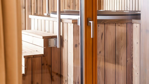 A wooden interior with a staircase leading to a higher level, a door with a handle, and a window with blinds.