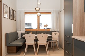 A modern kitchen with a built-in dining area, wooden cabinets, and a large window with curtains. - Apartment “N°2” with Mountain View, Private Terrace and Wi-Fi (Hüttschlag)