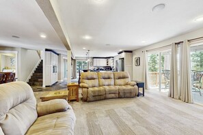 A spacious living area with a sofa, a dining table, and a kitchen in the background. - Spacious oasis with mountain views, 5 decks & foosball (South Lake Tahoe)