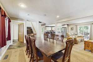 A spacious dining area with a long wooden table and chairs, a kitchen in the background, and a staircase leading to another level. - Spacious oasis with mountain views, 5 decks & foosball (South Lake Tahoe)
