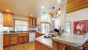 A kitchen with wooden cabinets, a central island, pendant lights, and a large window. - Spacious & Sunny Tahoe Donner Home - Enjoy Access to 5-Star Amenities (Truckee)