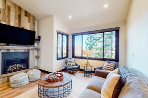 Un salon moderne doté d’une cheminée, de grandes fenêtres, d’un téléviseur à écran plat et d’un coin salon confortable.